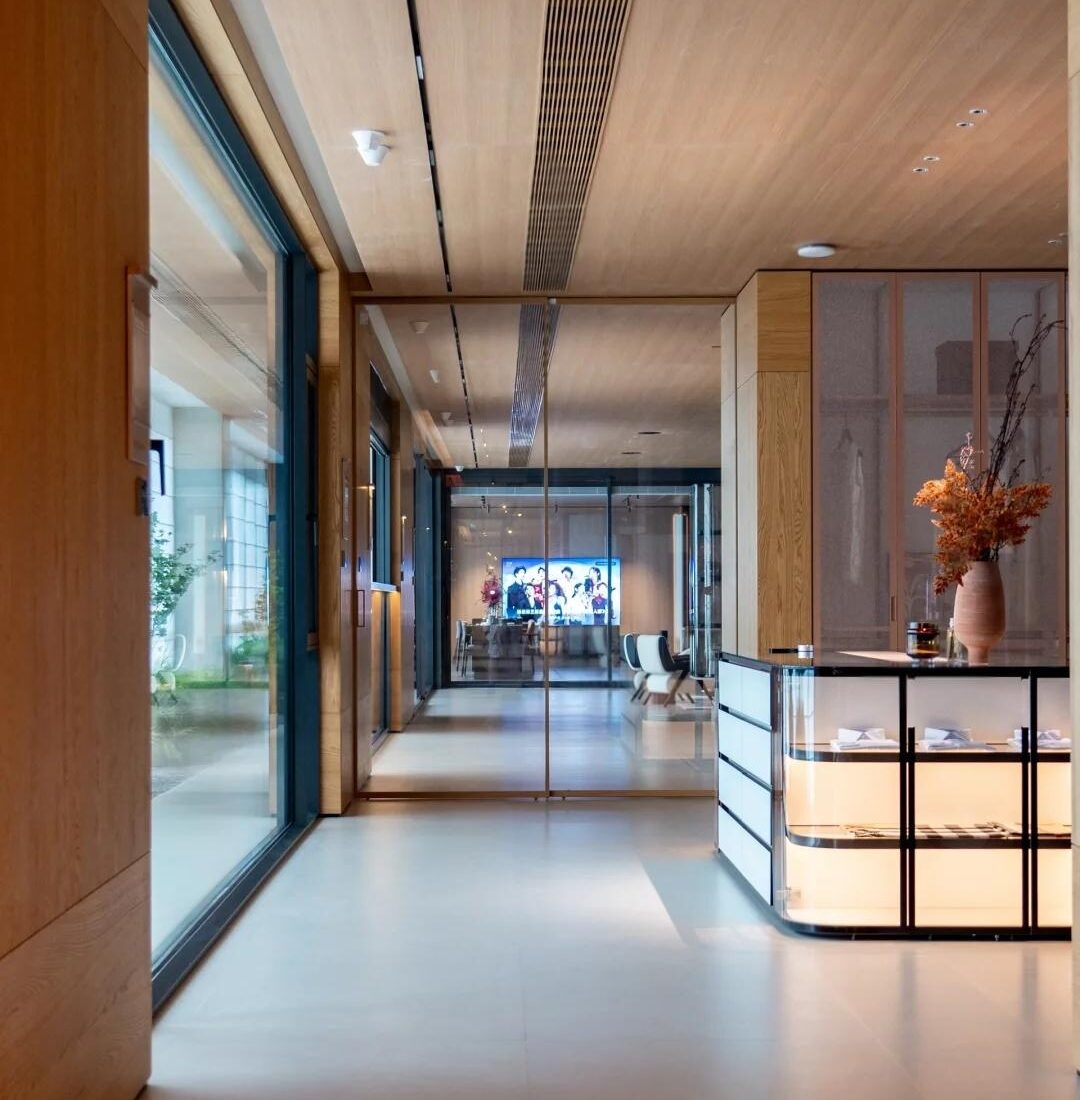 Corridor inside the HENNISSY Foshan headquarters showroom with glazed openings and an illuminated display cabinet