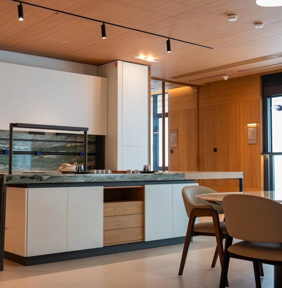 Kitchen display zone with a timber ceiling and stone island inside the HENNISSY Foshan headquarters showroom