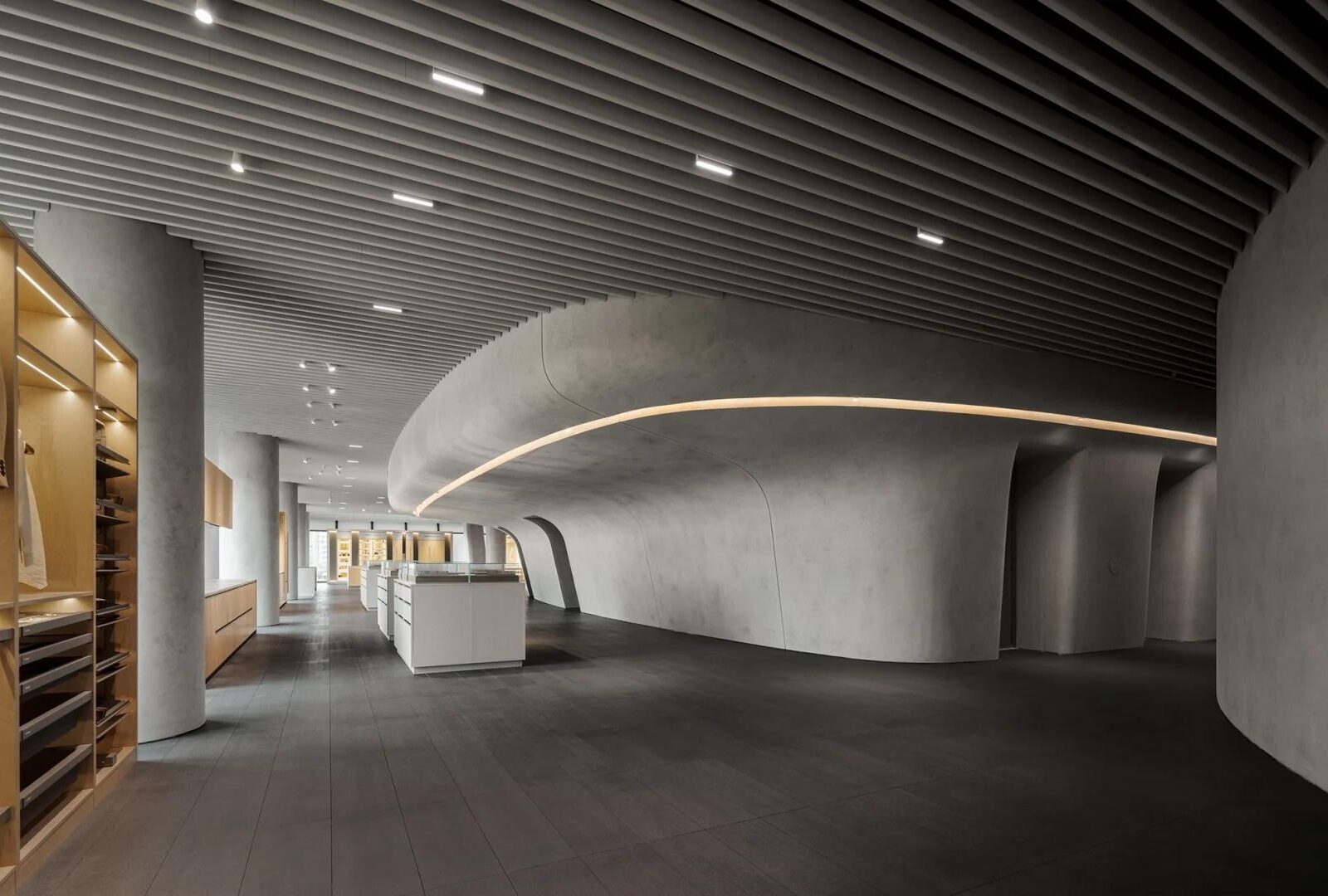 Wide interior view of the HIGOLD Future Hardware Pavilion in Foshan with curved concrete forms and storage displays